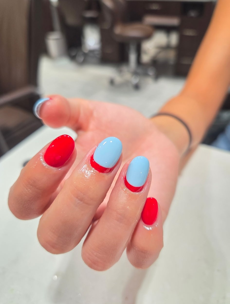 Short almond nails in cherry red and powder blue with color-blocked half-moon accents