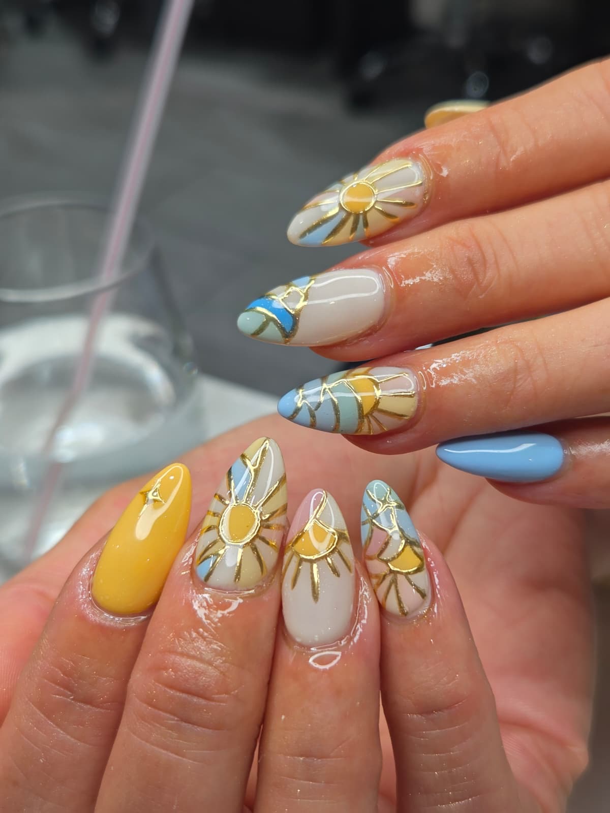 Almond nails with hand-drawn sunbursts outlined in raised gold